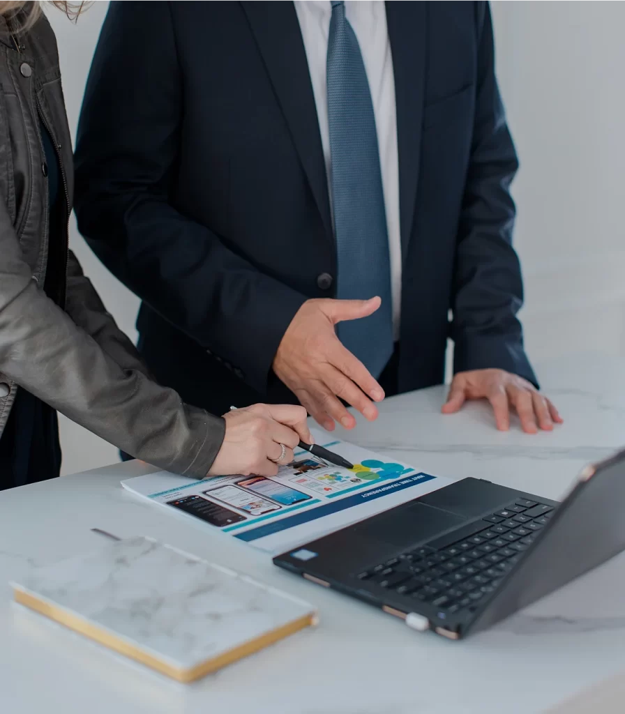 Business consultants discussing strategic business documents and high-quality results, reviewing digital transformation insights on a laptop.